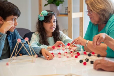 Grandmother playing educational games with grandchildren indoors, fostering creativity and learning.